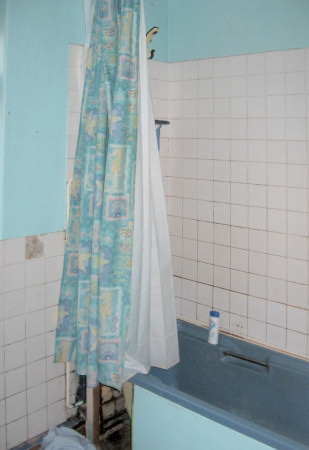 Electric shower over bath with shower curtain