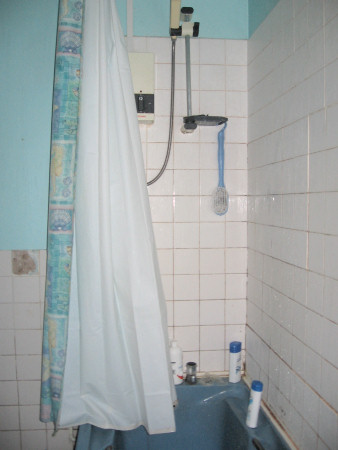 Electric shower over bath with shower curtain