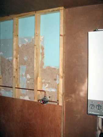 Wall by boiler plastered and shower plumbing laid in