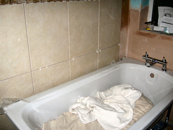 Tiling started on wall by door. NB bath is not in final position here.