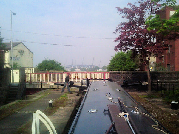 Narrowboat in lock with Manchester City stadium visible in background